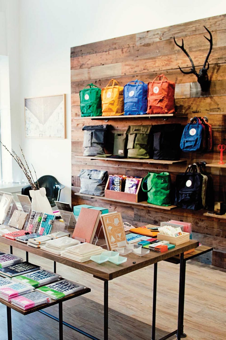 store display with journals on table and colorful backpacks on wall shelves