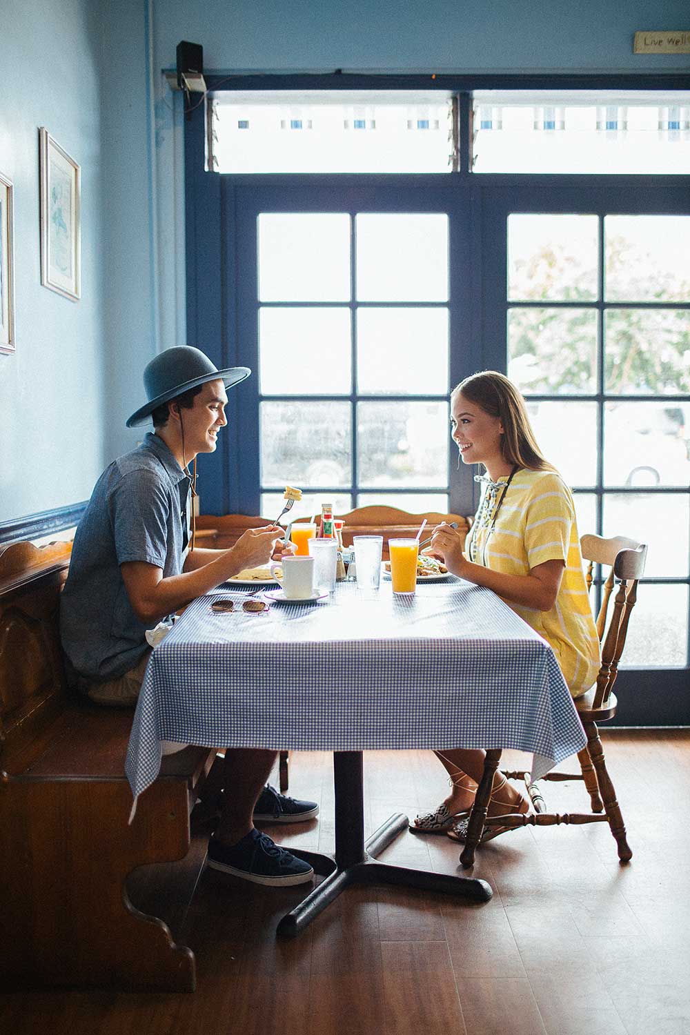 man in hat and woman in yellow dress sitting at breakfast table