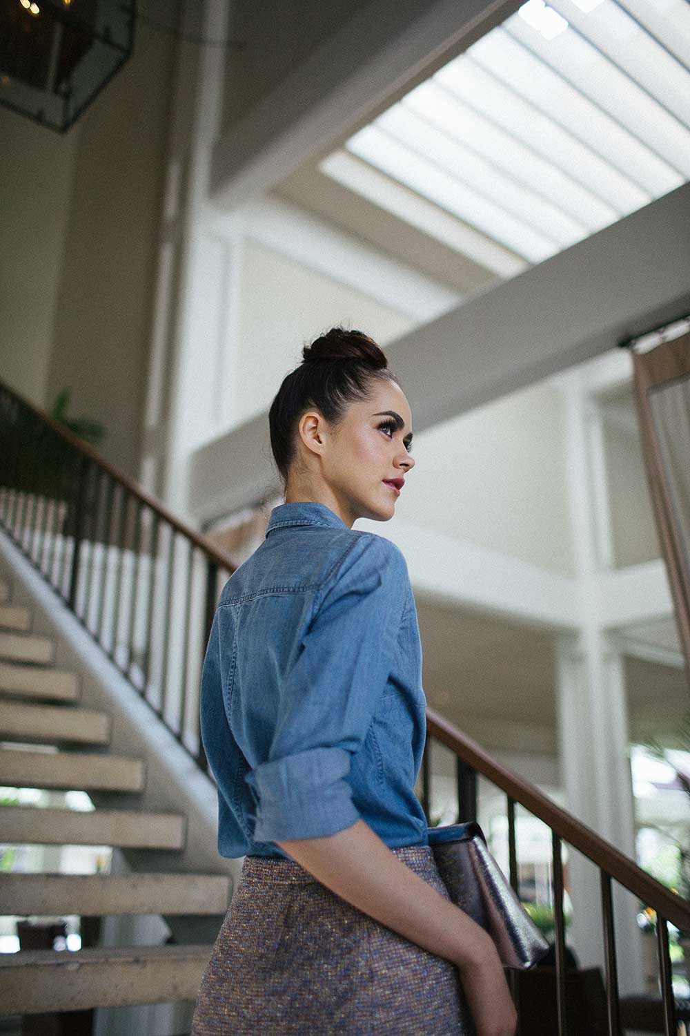 woman in jean shirt standing on stairway