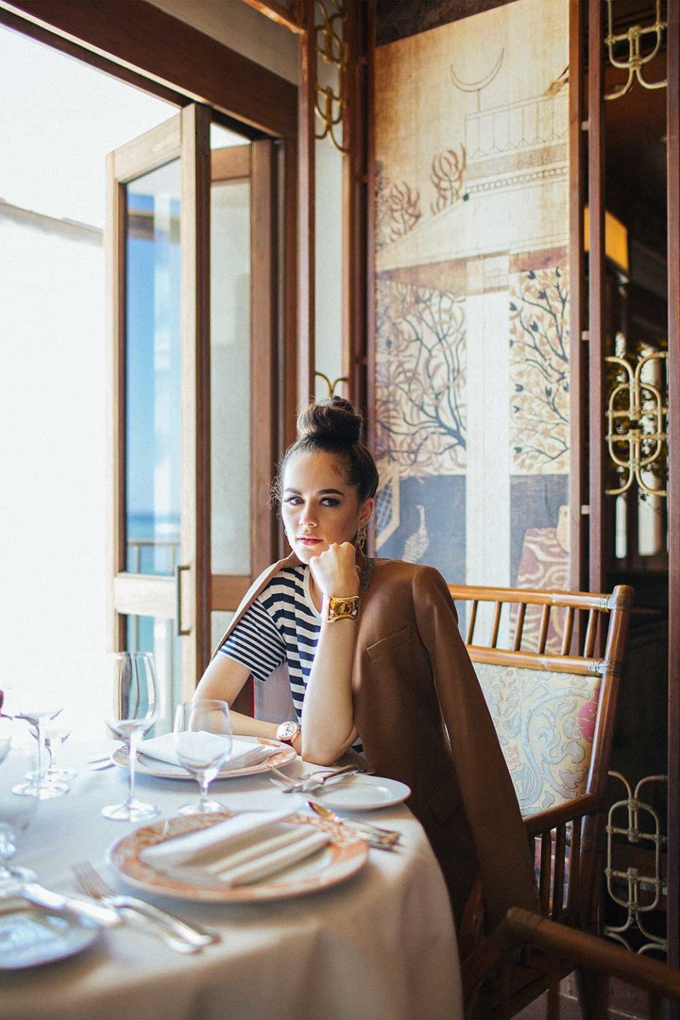 woman sitting at restaurant table with hand on her chin