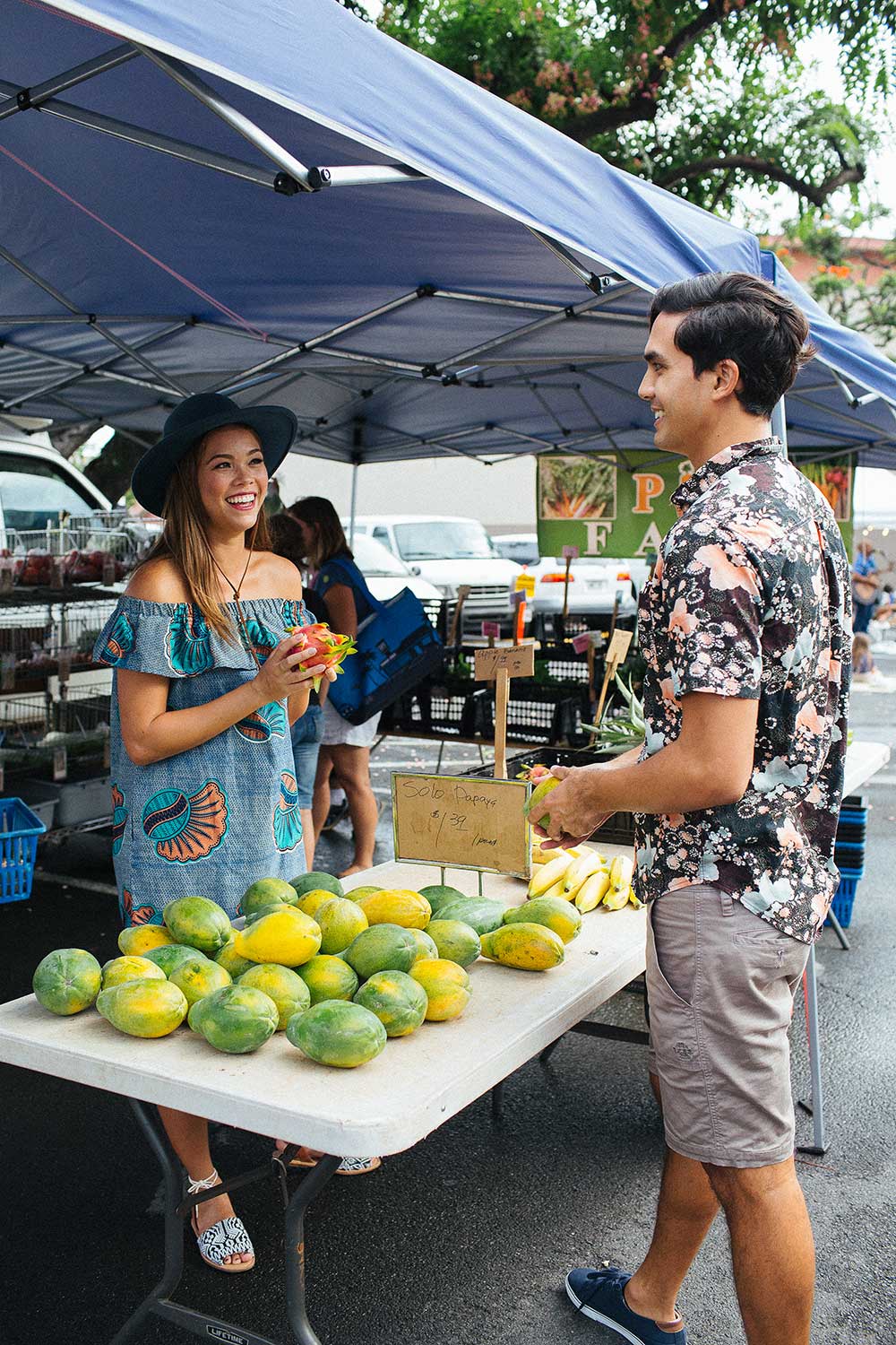 man and woman holding papayas smiling