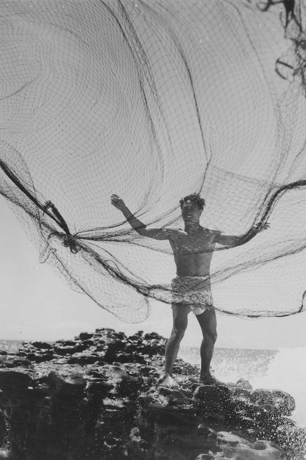 black and white photo of man casting fishing net