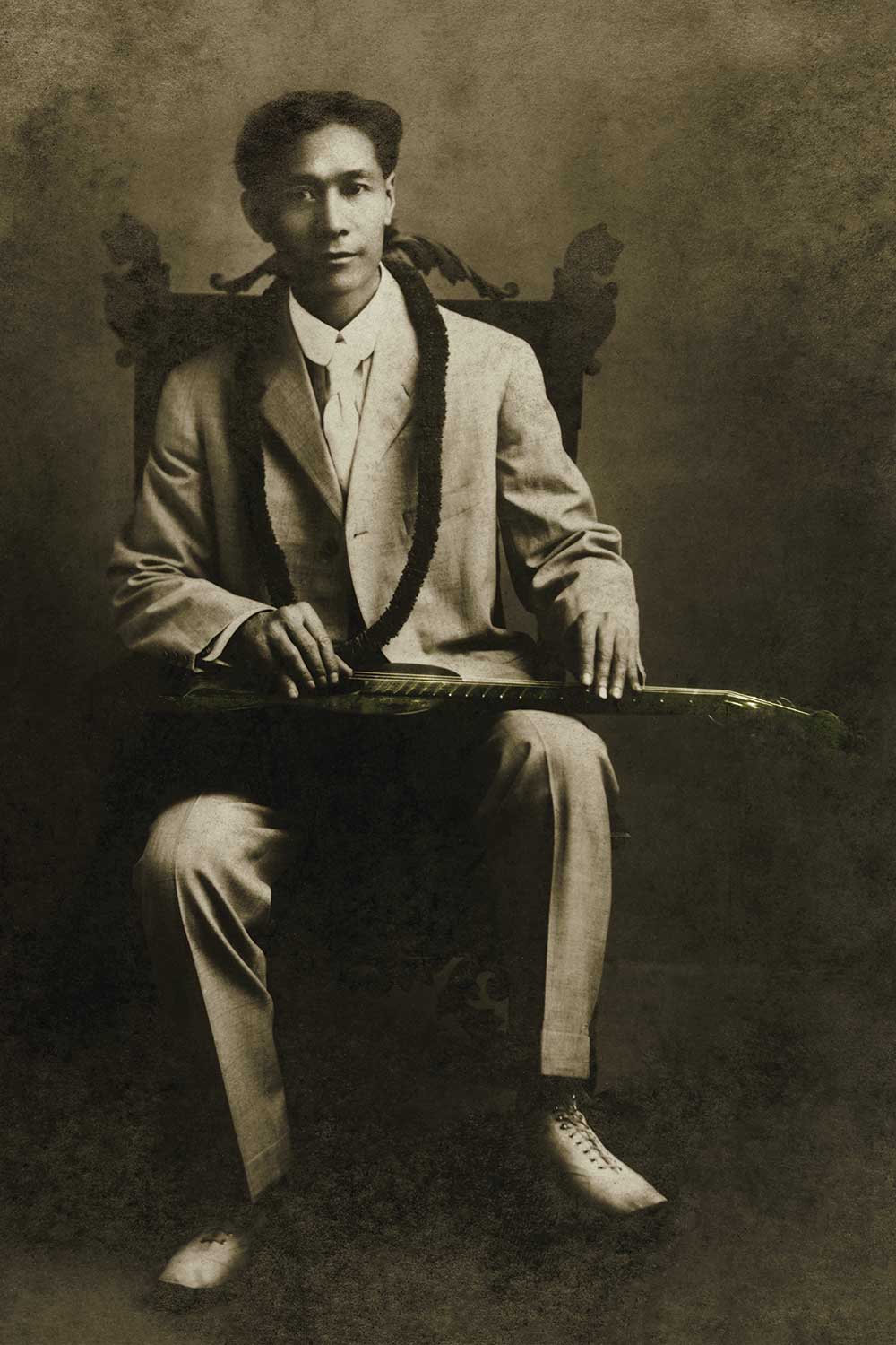 black and white photo of Joseph Kekuku with steel guitar on lap
