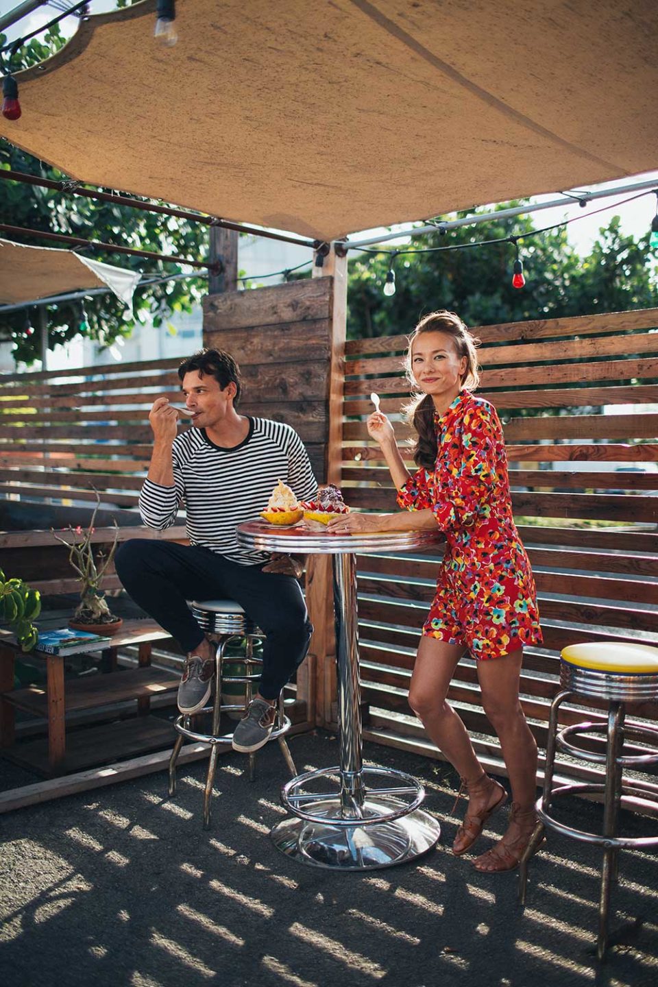 man and woman enjoying dessert on restaurant patio under umbrella