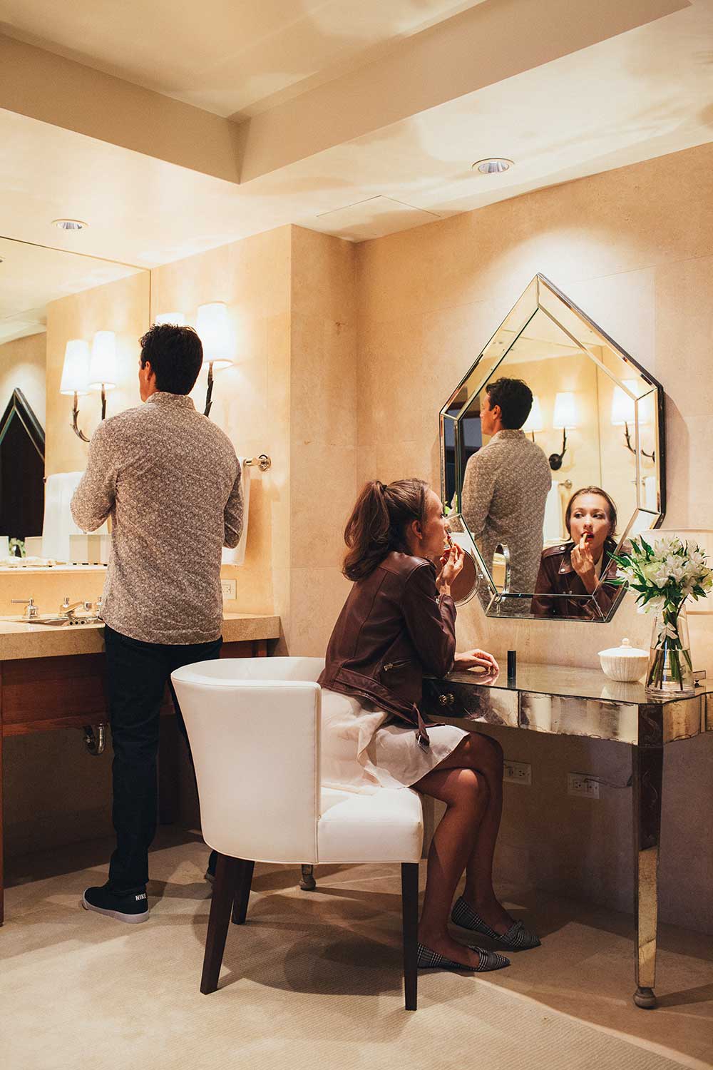 man and woman getting ready in mirror at hotel