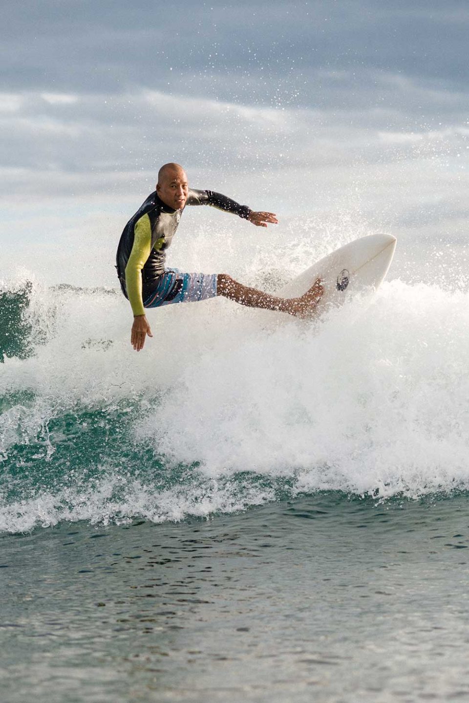 Guy Chang in wetsuit surfing a wave