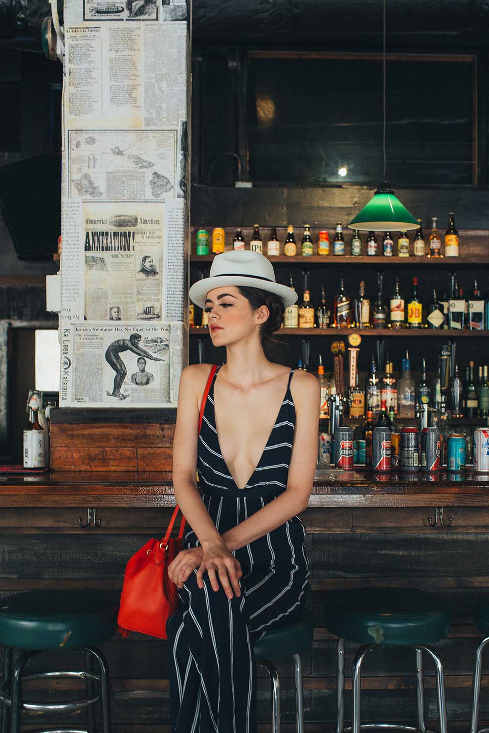 woman in black striped dress with red purse sitting on bar stool