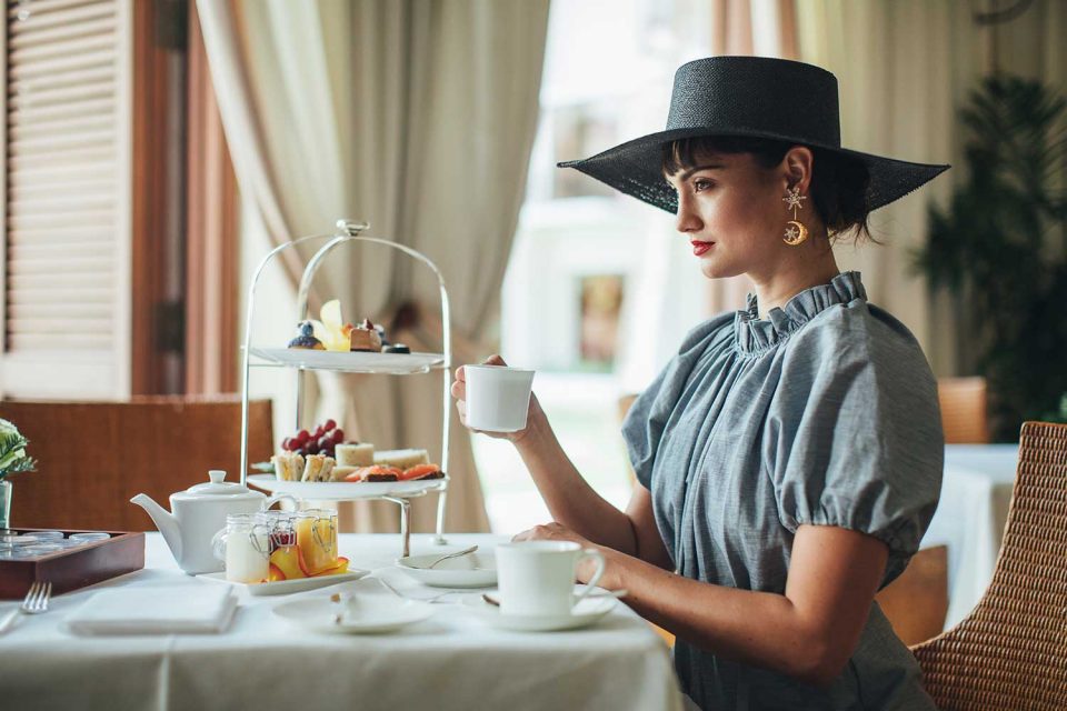 woman enjoying a cup of tea and finger foods.