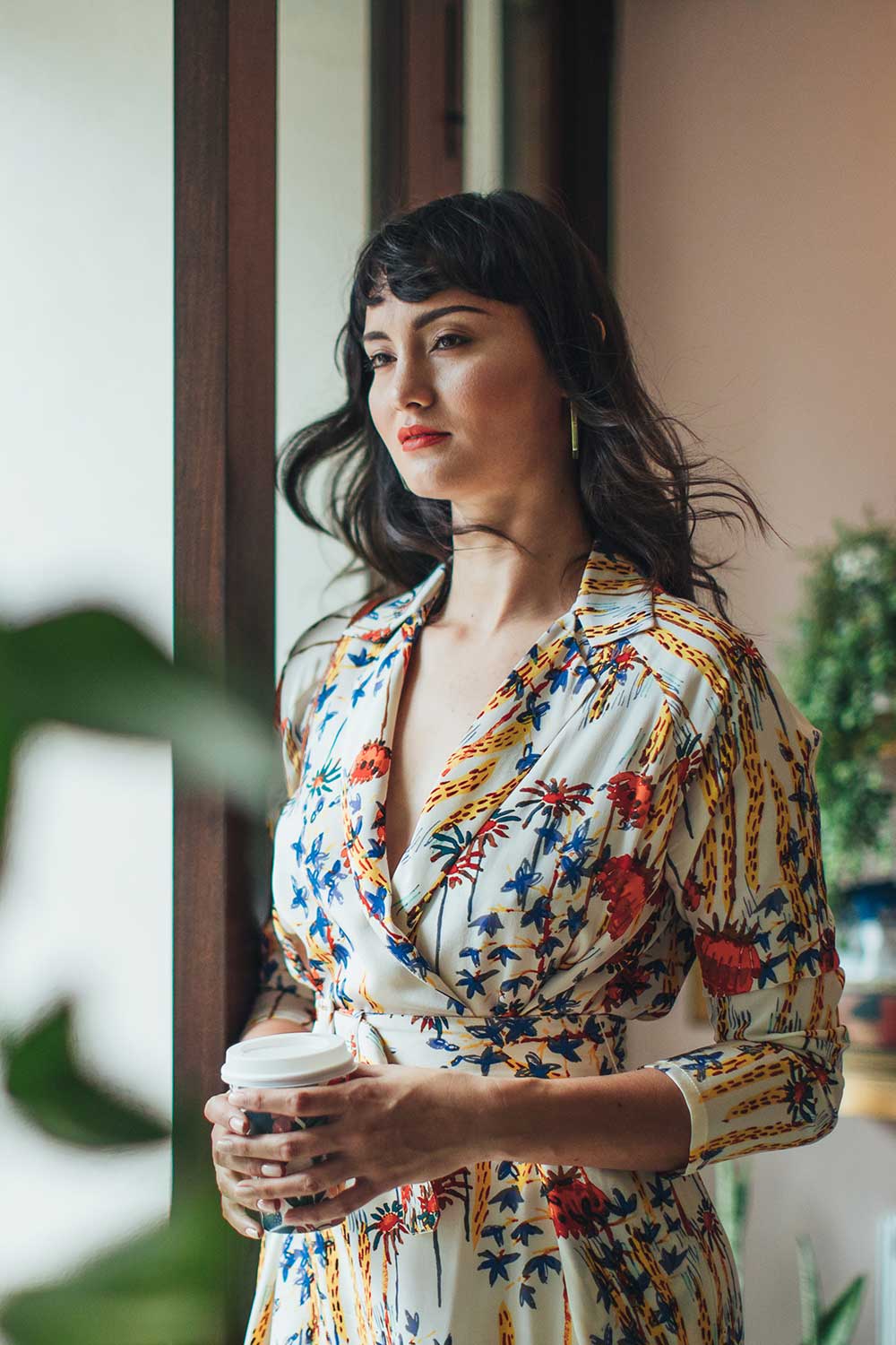 Woman with flower dress holding coffee.